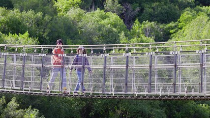 Wall Mural - Mother and son walking on suspension bridge enjoying mountain vacation. Trekking in mountains. Family in nature. Family backpacking.