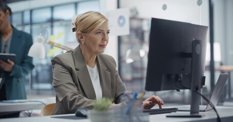 Poster - Female Financial Analyst Forecasts Market Trends on a Desktop Computer in a Modern Office with Diverse Colleagues. Middle Aged Manager Using Accounting Software to Analyze Financial Data