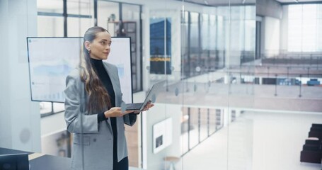 Poster - Confident Caucasian Woman Working on Laptop Computer in a Bright and Modern Office. Young Manager in a Grey Outfit Analyzing Market Trends and Developing Business Strategies for Corporate Clients