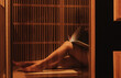 © Forewer - Close up of woman sitting on bench in infrared sauna, space for text. Spa treatment. Relaxing in sauna during wellness weekend. Soft focus, blurred