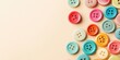 © Rufat - Vibrant multicolored sewing buttons in various sizes arranged randomly on a soft beige backdrop with ample space for text on the left side