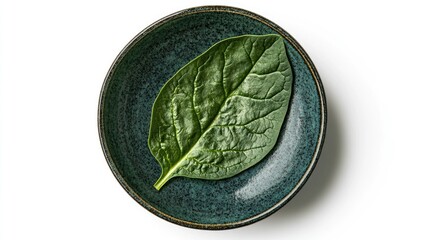 Aufkleber - Single fresh spinach leaf elegantly placed in a dark bowl against a white background showcasing natural textures and colors.
