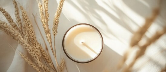 Poster - Relaxing home decor with a natural scented candle surrounded by dried wheat for a warm and cozy atmosphere in interior styling.