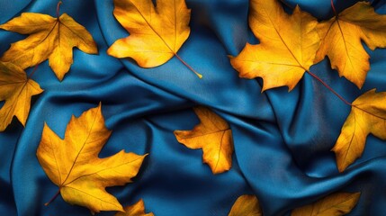 Poster - Silk fabric in vibrant blue with an elegant print of golden autumn leaves creating a luxurious texture pattern background