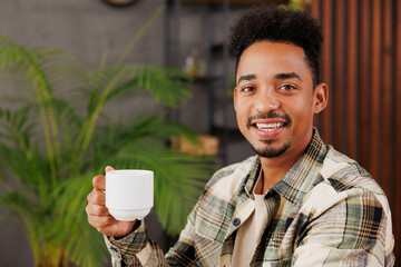 Sticker - Close up young minded man of African American ethnicity wear grey casual clothes drink tea enjoy moment sitting alone at table in coffee shop cafe relax rest in restaurant during free time indoors..