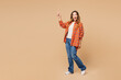 © ViDi Studio - Side profile view young surprised happy shocked woman wear orange shirt casual clothes walk go point finger aside isolated on plain pastel light beige background studio portrait. Lifestyle concept.