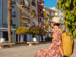 © YURII Seleznov - Woman in dress strolls through colorful streets of coastal town of La Vila Joiosa or Villajoyosa. Colorful homes in seaside villa of Villajoyosa in Southern Spain