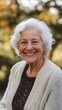 © Oleksandr - A heartwarming portrait of a senior woman with silver hair wearing a cozy cream cardigan, radiating joy with her genuine smile against a soft, natural bokeh background.