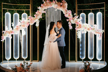 Wall Mural - bride and groom against the backdrop of an evening wedding arch