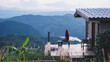 © Farknot Architect - A woman sitting on wooden house terrace and looking at a reservoir and mountain view