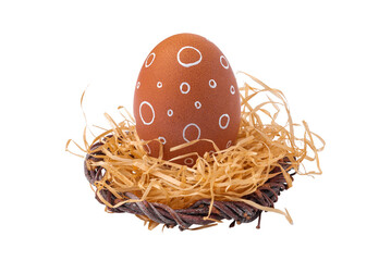 One Easter egg with a white ornament in a nest with straw isolated on a white background