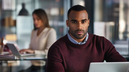 Aufkleber - Confident man working in a modern office while a colleague engages with her laptop in the background