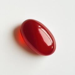 Poster - Bright red glossy jelly bean resting on a white surface, showcasing vibrant color and smooth texture