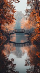 Aufkleber - Narrow bridge covered in vibrant autumn foliage reflects in calm waters of serene river at dawn