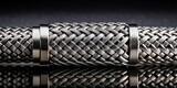 Close-up view of a braided metal hose with metallic end caps reflecting on a dark surface