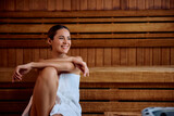 Young smiling woman relaxing in sauna at wellness center.