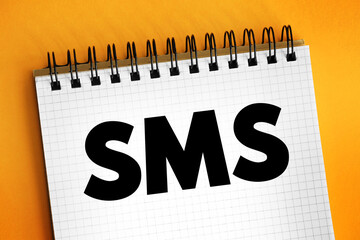 Poster - SMS (Short Message Service) - text messaging service component of most telephone, Internet and mobile device systems, text concept on notepad