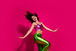 © deagreez - Young woman dancing energetically in vibrant pink and green outfit against bright magenta background