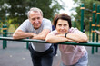 © caftor - Portrait of an elderly couple in sportswear on sports ground in a city park on summer day