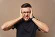 © muse studio - Man expressing frustration while holding his head in a neutral backdrop