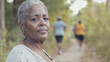© Dirk - Aging black african american woman, walking on a walking trail, exercise outdoors, some other people in background. Elderly black woman in good health, walking or jogging outdoors. Senior black woman.