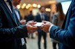 © Viktor - Businesspeople exchange business cards at professional networking event in modern conference hall. Attendees in formal wear interact casually. Atmosphere energetic, productive. Successful business