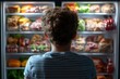 © tantawat - Young Consumer Standing in Front of Open Refrigerator Looking Inside