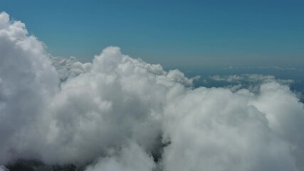 Wall Mural - flying through beautiful white fluffy clouds in sky over blue sea. airplane travel background, 4k