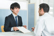 © buritora - 受付・窓口で男性客を接客する若いアジア人ビジネスマン