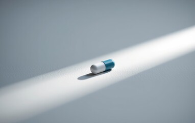 Wall Mural - A single  capsule pill resting on a clean white surface, casting a subtle shadow.