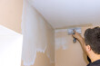 © ungvar - Worker is smooths plaster corners of beige wall, engaged in home improvement