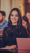 © Siasart Stock - Smiling Young Woman Sits at Table with Laptop and Notebook in Classroom, Focused and Engaged