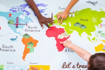 Aufkleber - Children's hands exploring a colorful world map. Kids pointing at continents like Africa, Europe, and Asia. Educational map for children learning geography. Geography class in school with map.