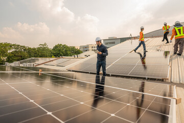 Wall Mural - Men technicians carrying photovoltaic solar moduls on roof of factory on the morning. Installing a Solar Cell on a Roof. Solar panels on roof. Workers installing solar cell power plant eco technology.