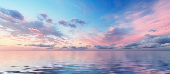 Wall Mural - twilight sky with soft pink and blue hues behind clouds over a calm azure water surface reflecting t