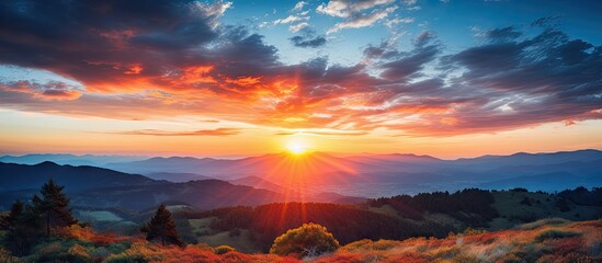 Wall Mural - vibrant sunset over mountain range with layered clouds in shades of orange, pink, and blue creating 