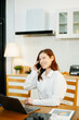 © Nuttapong punna - Woman using laptop while sitting at home. Young woman sitting in kitchen and working