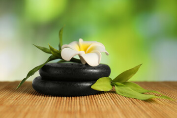 Wall Mural - Spa stones, plumeria flower and green leaves on bamboo mat, closeup