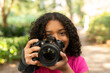 © Cavan Images - Young photographer taking photo in a park with professional camera