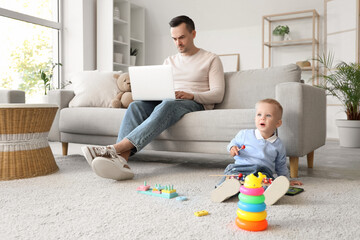 Canvas Print - Little boy playing with toys while his father working at home