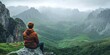 © Irina Ukrainets - A serene landscape featuring a person sitting on a rock. The view includes rolling hills and majestic mountains in a misty atmosphere. Perfect for nature lovers and adventurers. AI
