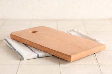 Empty cutting board with napkins on white tiled table, closeup