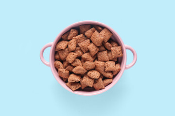 Poster - Bowl with tasty chocolate corn pillows on blue background