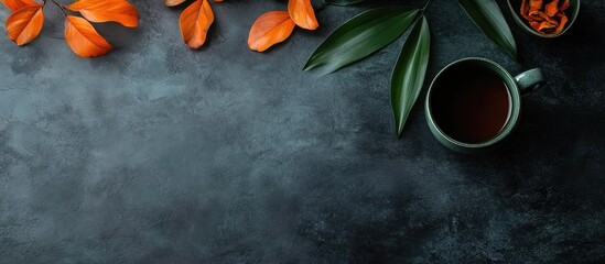 Poster - Steaming black tea in a large dark green teacup on a rustic writing desk with orange leaves and greenery, ideal for relaxation and contemplation.
