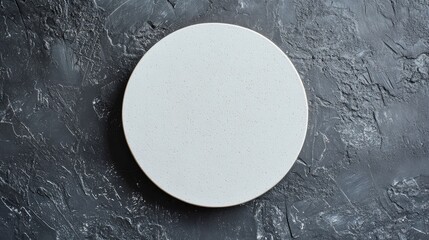 Aufkleber - Aerial view of a minimalist round white plate centered on a textured dark gray stone surface, ideal for culinary presentations and food styling.