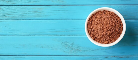Poster - Cocoa powder in a white bowl positioned on a vibrant blue wooden table top with ample negative space for text or design elements.