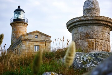 Poster - A lighthouse sits atop a lush green hillside, offering a beacon of guidance