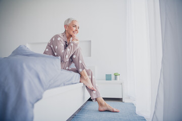 Wall Mural - Charming elderly woman in pajamas waking up in her bright, cozy bedroom