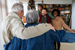 © NDABCREATIVITY - Excited multiethnic family greeting grandparents on Christmas Day. Multi-generational happy family