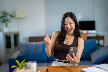 Wall Mural - A woman is sitting at a table with a cell phone in her hand, smiling